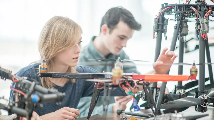 Eine Gruppe von Studenten arbeitet daran, eine Maschine mit Drohnenteilen zu bauen, sie lernen und arbeiten zusammen in einer Universitätsklasse.
